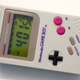 A closeup of the Paladone Game Boy digital watch, photographed on a white wood side table.